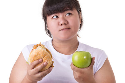 Portrait of smiling woman holding apple against white background