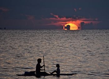 Silhouette of man in sea at sunset