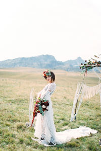 Full length of bride standing on field against sky