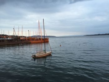 Boats in sea against cloudy sky