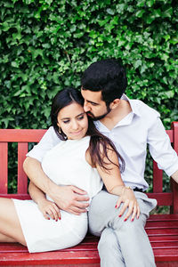 Couple romancing while relaxing on bench at park