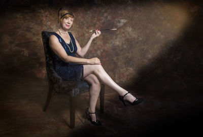 Portrait of woman sitting on chair against wall