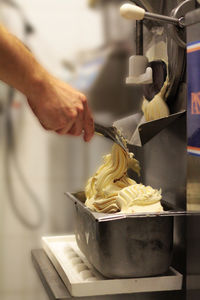 Cropped hand of man preparing ice cream in factory