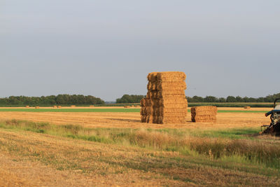 Hay bales on field against clear sky