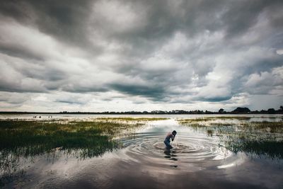 Man surfing on lake against sky