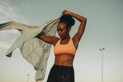 Female athlete wearing jacket against sky during sunset