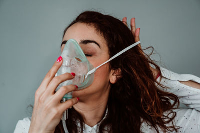 Woman wearing oxygen mask against gray background