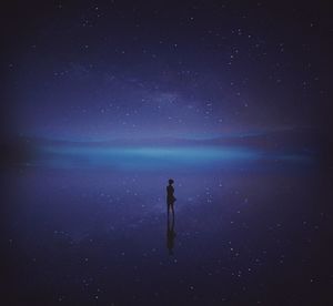 Man standing in sea against sky at night