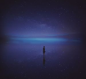 Man standing in sea against sky at night