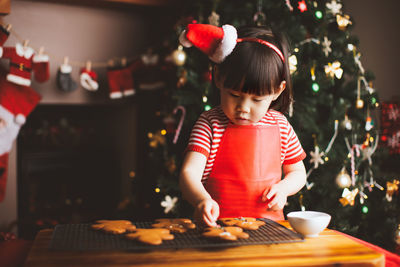 Girl preparing cookies on table during christmas