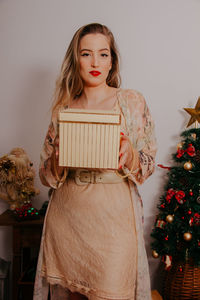 Young woman standing by christmas tree