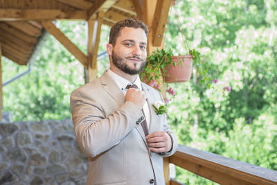 Portrait of man holding necktie by railing