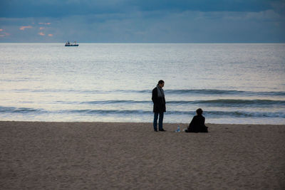 Silhouette people on beach against sky at dusk