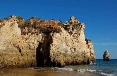 Rocky cliff and sea against sky 