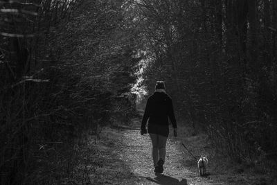 Rear view of woman with dog walking in forest