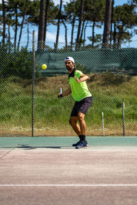 Full length of man playing tennis at court