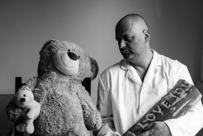 Man looking at teddy bears against wall