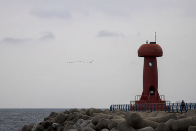 Lighthouse by sea against sky