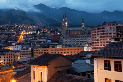 Illuminated city against mountains at twilight