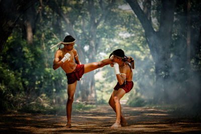 Full length of shirtless warriors fighting in forest