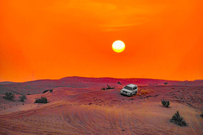 Scenic view of desert against orange sky during sunset