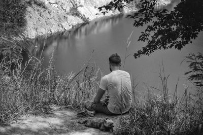 Rear view of man sitting by lake