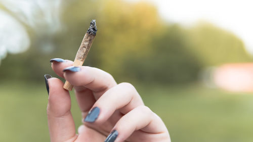 Close-up of woman hand smoking marijuana joint outdoors