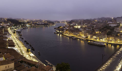 High angle view of illuminated buildings by river against sky