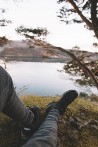 Low section of man by river against sky