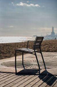 Chair on beach against sky