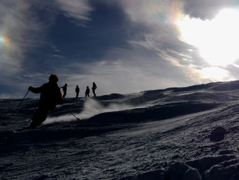 Low angle view of silhouette person skiing downhill against sky on sunny day