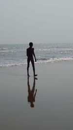 Silhouette man walking on beach against clear sky