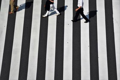 Low section of man walking on zebra crossing during sunny day