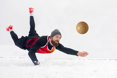 Full length of young man playing volleyball in snow
