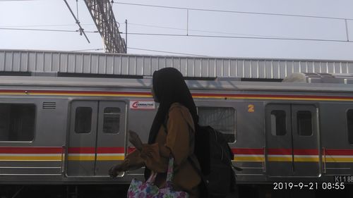 Rear view of woman standing on train at railroad station