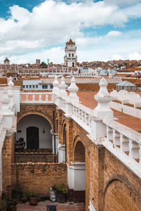 Church amidst buildings against cloudy sky in city