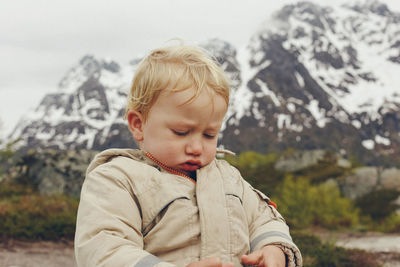 Cute boy against snow covered mountains