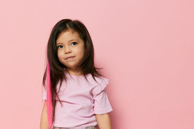 Portrait of young woman standing against pink background