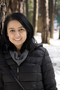 Portrait of happy mid adult woman wearing warm clothing while standing outdoors