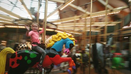 Rear view of girl riding horse at amusement park