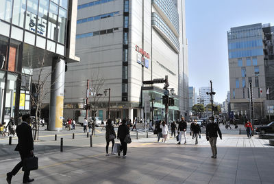 People walking on street by modern buildings in city