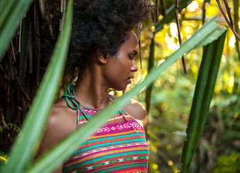 Portrait of young woman looking through plants