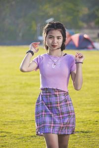 Portrait of young beautiful woman standing in the wind on the green lawn