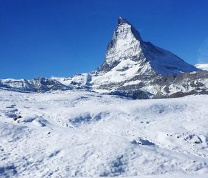 Scenic view of snowcapped mountains against clear blue sky