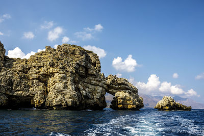 Rock formation in sea against sky