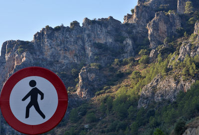 Road sign by rock formation against sky