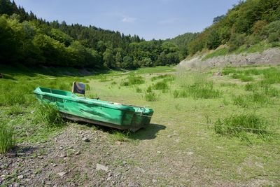 Boat on land by trees against sky