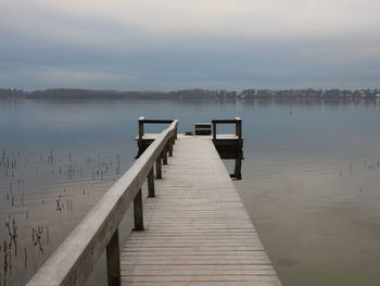 Wooden pier on lake against sky