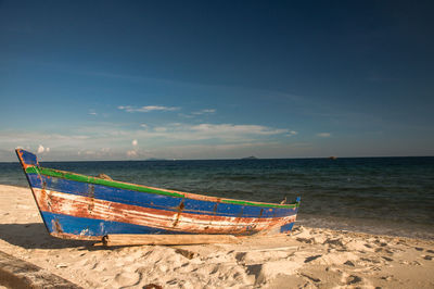 Boat moored on beach against sky