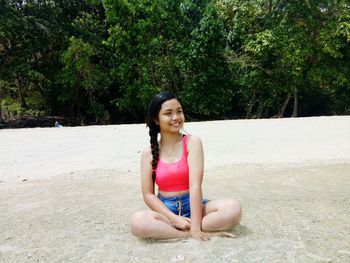 Portrait of smiling young woman sitting on land